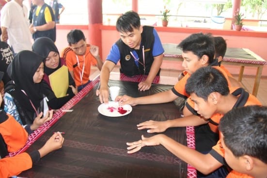 One UTM students (black vest) facilitate participants doing the group activities at SciMEx 2014 at Bandar Tenggara
