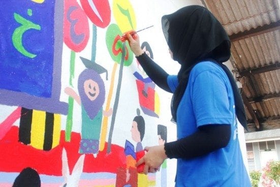The UTM JETS 2015 participants assisting the Sekolah Agama Felda Sening pupils in painting the school building.