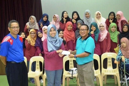 Nurfatiha Ramli (second left) handing over the donation to the representative from Cerebral Palsy Society.