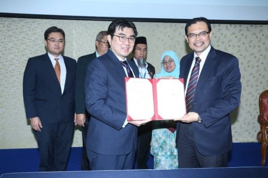 Raymond Tang (left) exchanging documents with Prof. Azlan after the signing ceremony between UTM- Pentalight at Banquet Hall, UTM Johor Bahru.