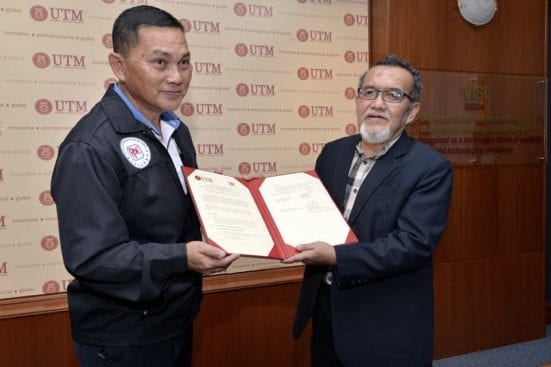 The PPCK President, Lim Kham Hong (left) holding the agreement documents with Prof. Muhd Zaimi Abd. Majid after the signing ceremony between UTM KALAM and PPCK at UTM Main Meeting Room