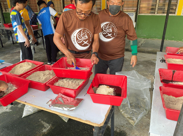 Penternak menggaulkan bahan untuk dimasukkan ke dalam TMR